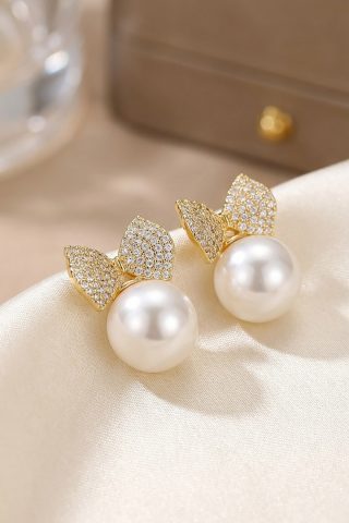 Κομψά σκουλαρίκια με πέρλα κεντρικά και χρυσούς φιόγκους διακοσμένους με ζιργκόν. Ιδανικά για elegant εμφανίσεις από το πρωί έως το βράδυ.